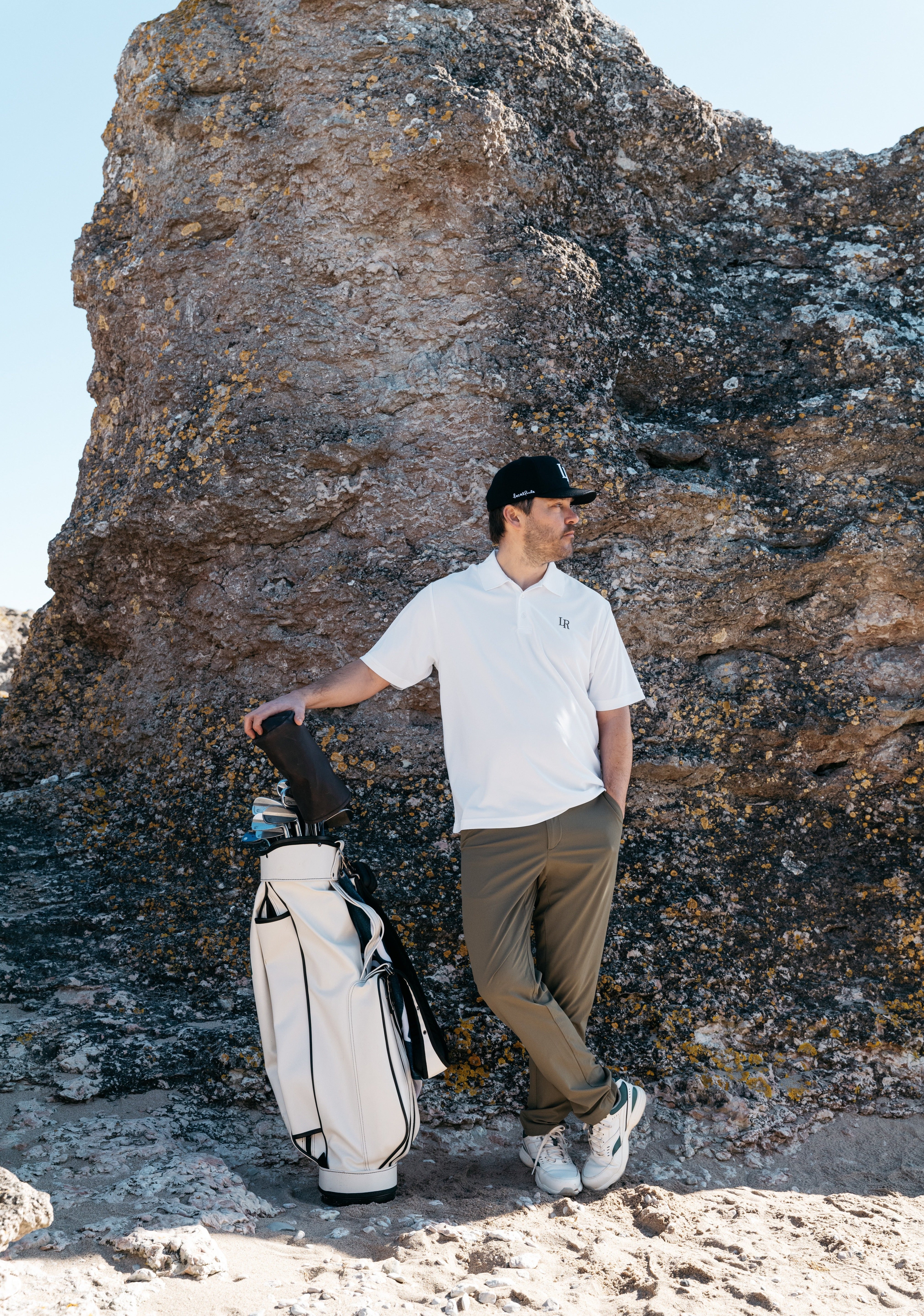 Man i modern golf outfit med tekniska plagg på golfbana, lager anpassade efter väder, golf outfit tips herr