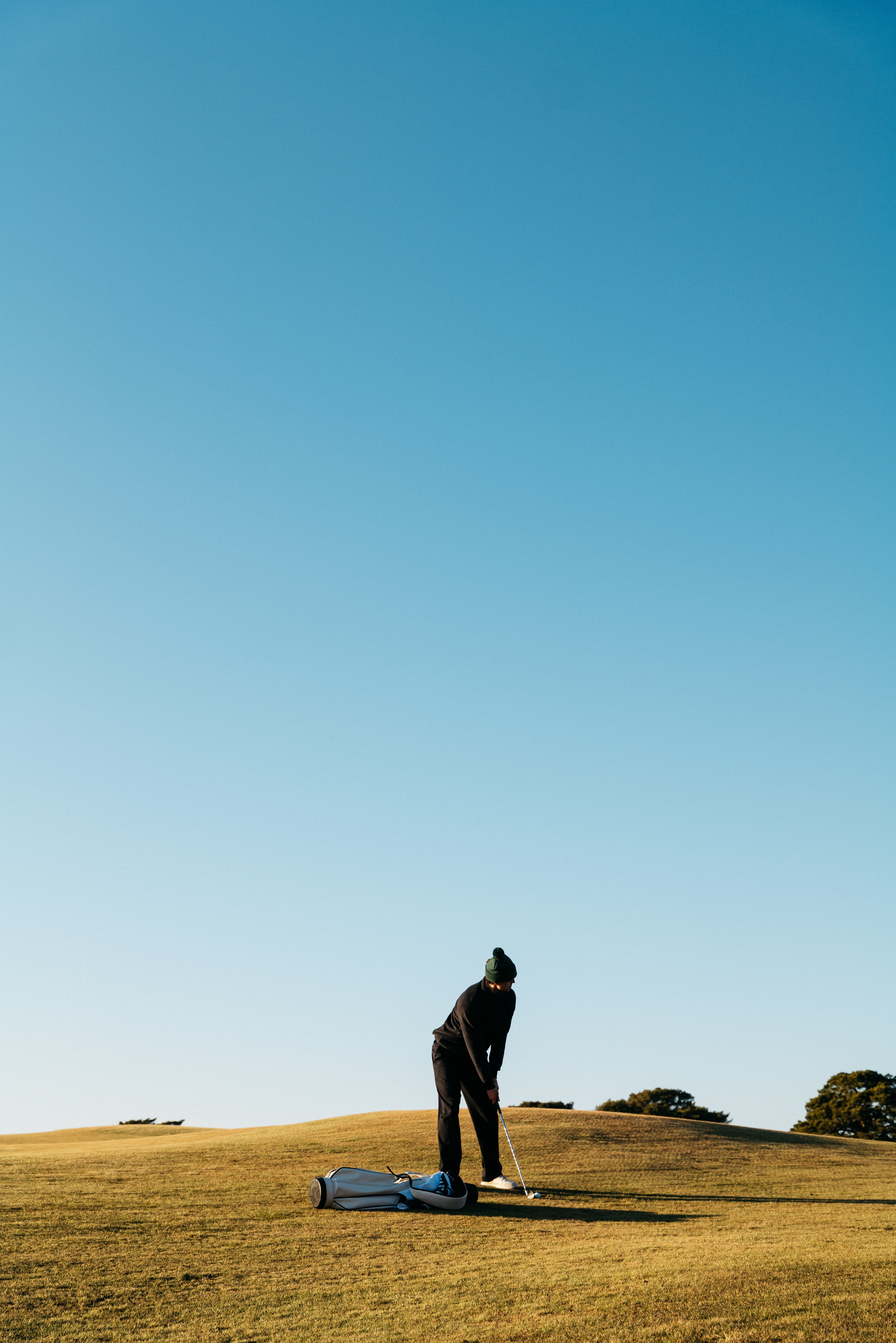 Golfer demonstrating how to swing a golf club with proper setup and smooth motion, wearing premium golf apparel on a green fairway