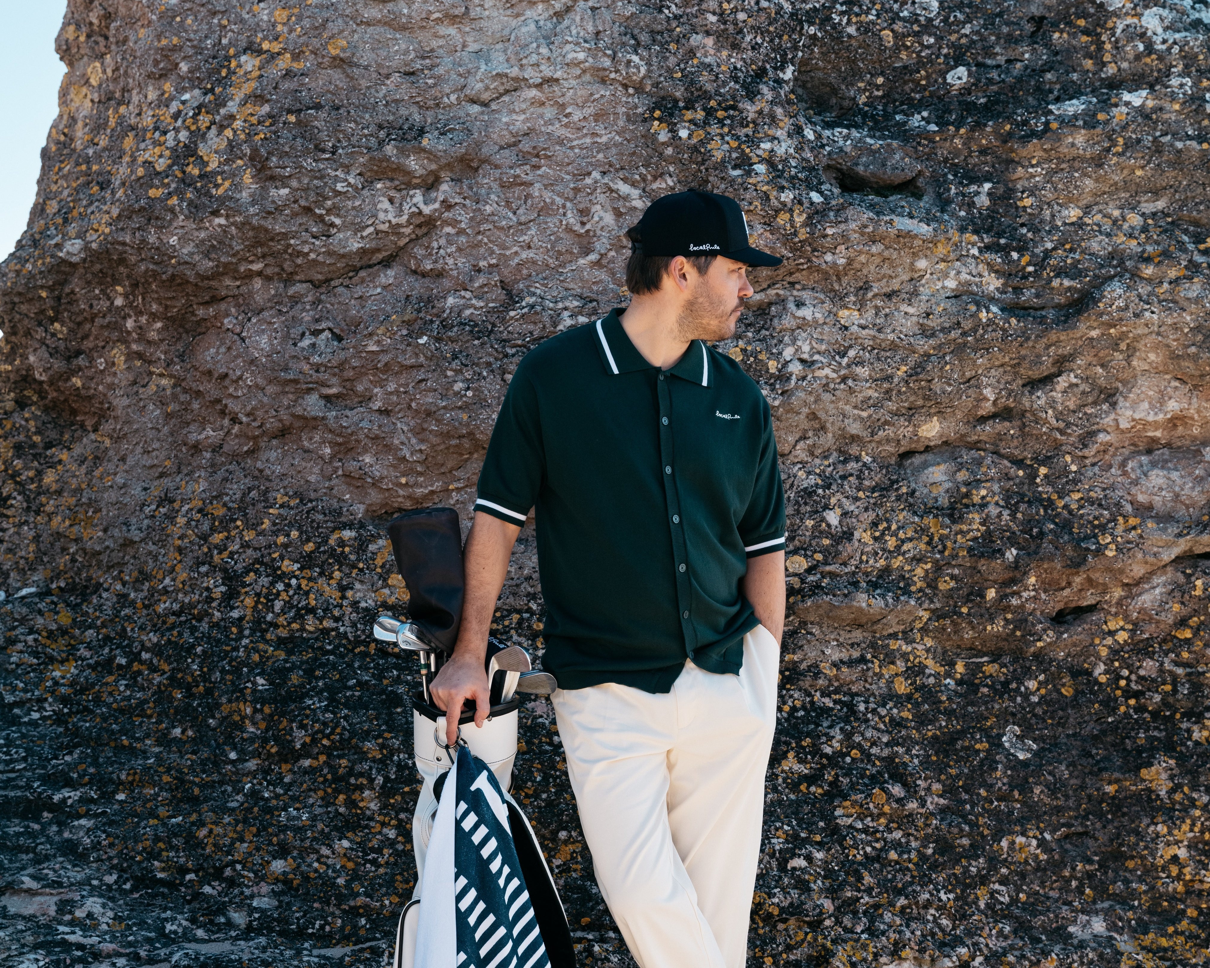 Golfare klädda enligt golf dresscode står på fairway nära klubbhus i stilrena och funktionella kläder